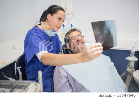 Smiling dentist showing x-ray to her patient Smiling dentist showing x-ray to her patient 13547640