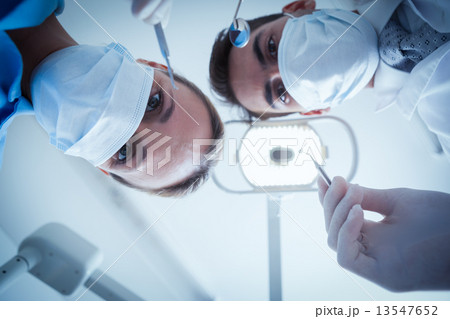Dentists in surgical masks holding dental tools 13547652