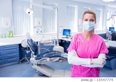 Dentist in surgical mask standing with arms folded Dentist in surgical mask standing with arms folded 13547774