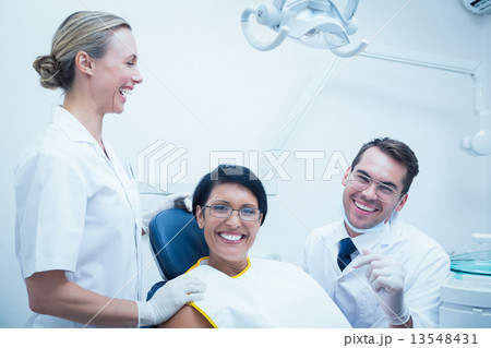 Cheerful dentist and assistant with female patient 13548431