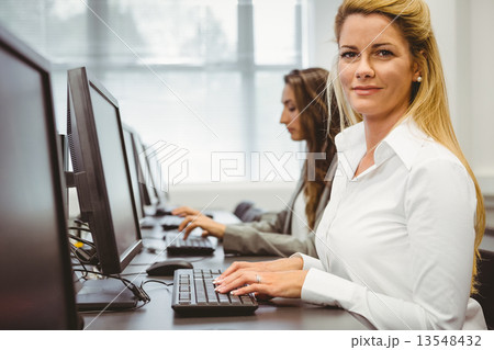 Happy woman in computer room smiling at camera Happy woman in computer room smiling at camera 13548432