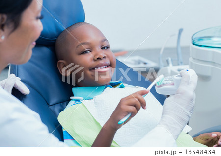 Dentist teaching happy boy how to brush teeth 13548434