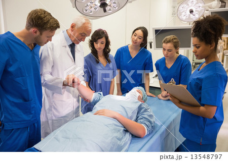 Medical students and professor checking pulse of student Medical students and professor checking pulse of student 13548797