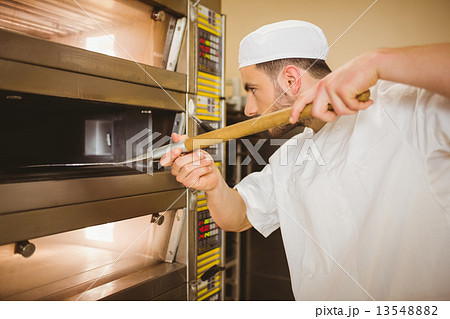 Baker taking bread out of oven 13548882