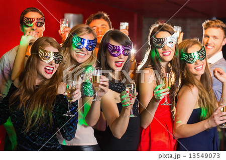 Friends in masquerade masks drinking champagne 13549073