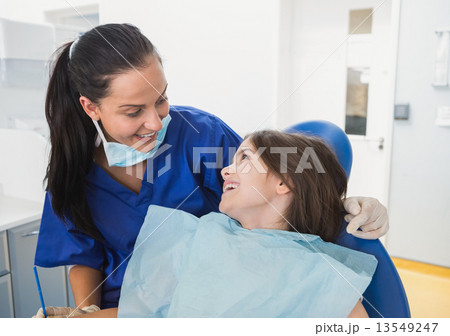 Cheerful pediatric dentist with a smiling young patient 13549247