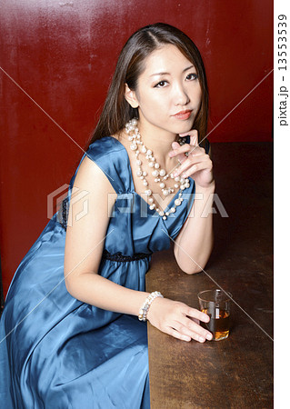 赤い壁のカウンターに座るカクテルドレスの女性 13553539