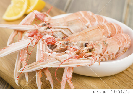 Bowl of boiled langoustines with lemon wedges 13554279