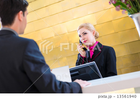 Hotel receptionist with phone and guest Hotel receptionist with phone and guest 13561940