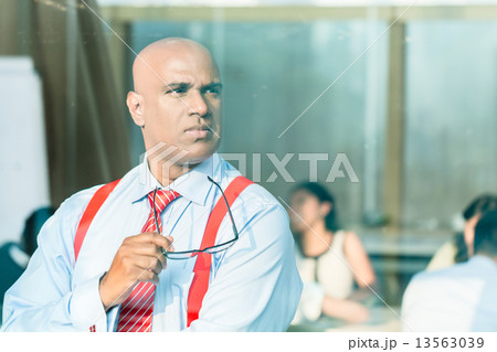 Indian Businessman thinking at office window Indian Businessman thinking at office window 13563039
