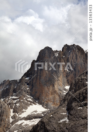 Rocks with snow and cloudy sky 13563433