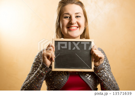 smiling woman holding small blackboard and looking at camera smiling woman holding small blackboard and looking at camera 13571639