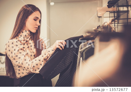 Young woman choosing clothes on a rack in a showroom 13572677