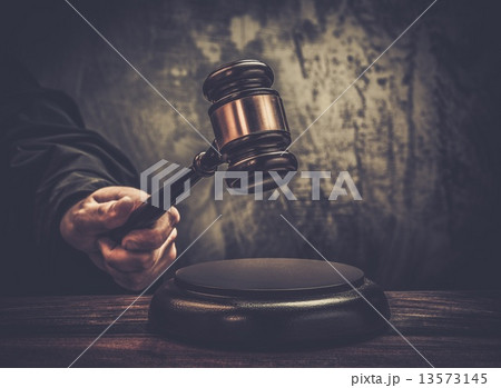 Judge's hand holding wooden hammer 13573145