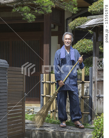 ほうきを持って立つ中高年男性 13591978