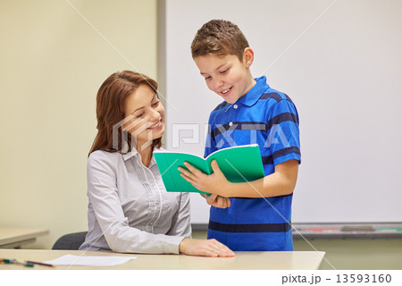 school boy with notebook and teacher in classroom school boy with notebook and teacher in classroom 13593160