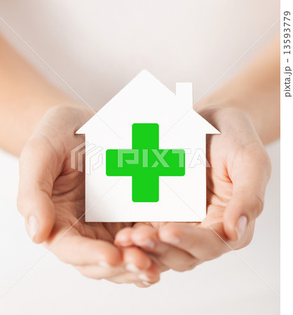 hands holding paper house with green cross hands holding paper house with green cross 13593779