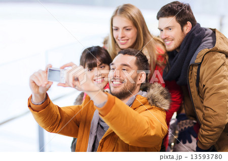 happy friends with camera on skating rink 13593780