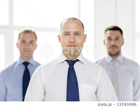 serious businessman in office with team on back serious businessman in office with team on back 13593986