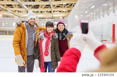 happy friends taking photo on skating rink 13594154
