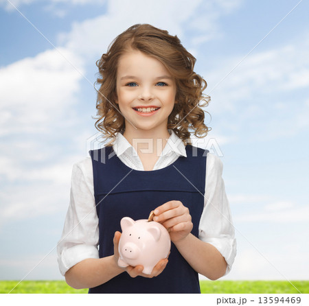 smiling girl putting coin into piggy bank smiling girl putting coin into piggy bank 13594469