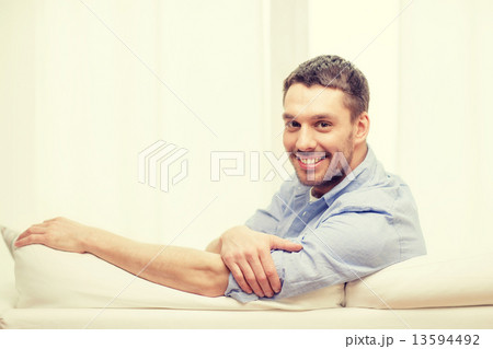 smiling man sitting on sofa at home 13594492