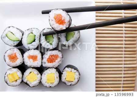 Chopsticks holding sushi from a plate of assorted sushi 13596993