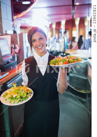 Pretty barmaid holding plates of salads Pretty barmaid holding plates of salads 13602821