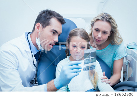 Dentist with assistant showing girl her mouth x-ray 13602900