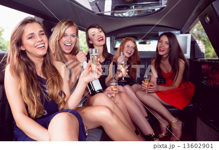Happy friends drinking champagne in limousine 13602901