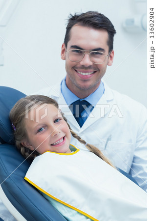 Male dentist examining girls teeth 13602904