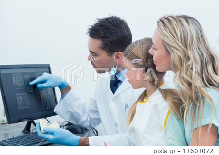 Dentist and assistant showing little girl her mouth x-ray 13603072