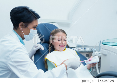 Female dentist teaching girl how to brush teeth Female dentist teaching girl how to brush teeth 13603129