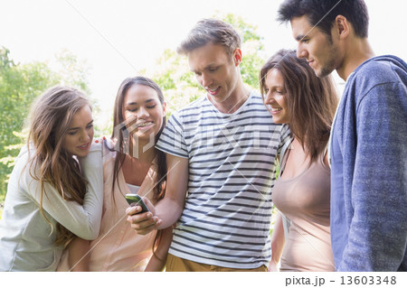 Happy students looking at smartphone outside on campus 13603348