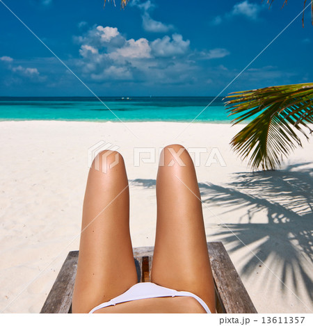 Woman at beach lying on chaise lounge 13611357