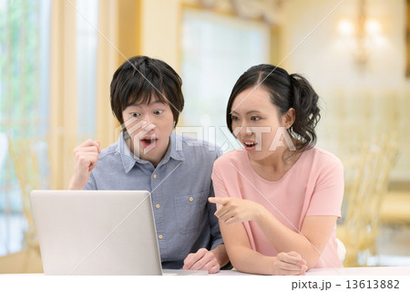 カフェで寄り添ってパソコンをしている20代カップル 13613882