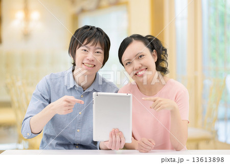 カフェで寄り添ってタブレットをしている20代カップル カフェで寄り添ってタブレットをしている20代カップル 13613898