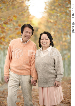 秋の並木道を散歩する中年のカップル 13614532