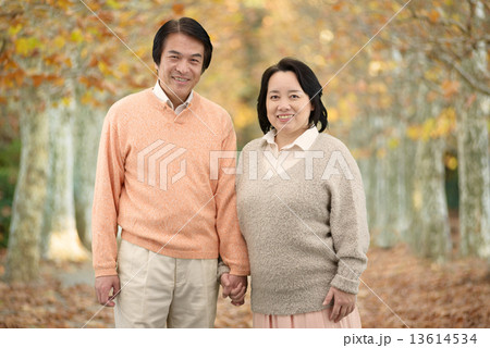 秋の並木道を散歩する中年のカップル 13614534