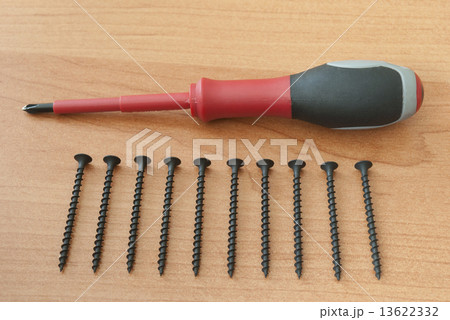 Screwdriver and screws are on a wooden board 13622332