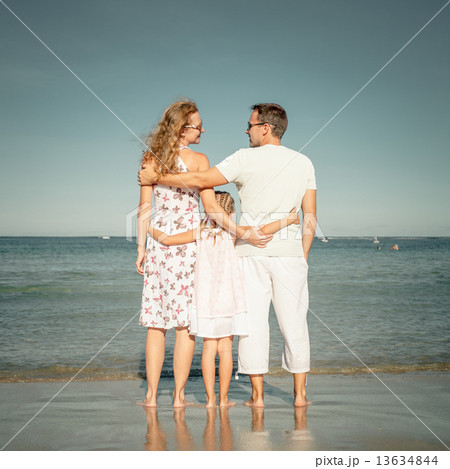 Happy family standing at the beach at the day time Happy family standing at the beach at the day time 13634844