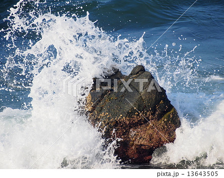 岩に砕け散る波しぶきの写真素材