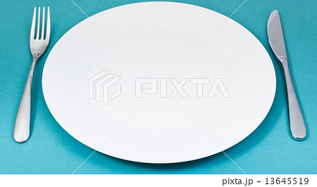 empty white plate with fork and knife set on green 13645519