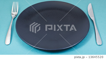 dinner black plate with fork and knife on green dinner black plate with fork and knife on green 13645520