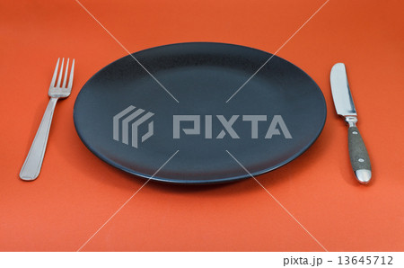 empty black plate with fork and knife set on red empty black plate with fork and knife set on red 13645712