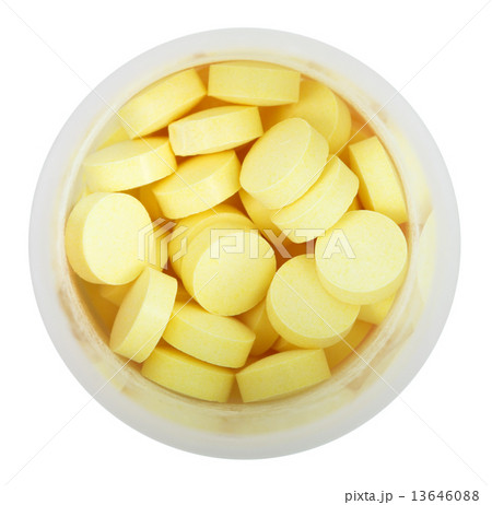 yellow pills in round plastic bottle close up 13646088