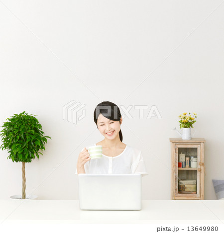 パソコンの前に座って笑う女性 13649980
