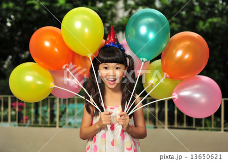 A cute Asian girl is posing with many colourful balloons at her birthday party 13650621