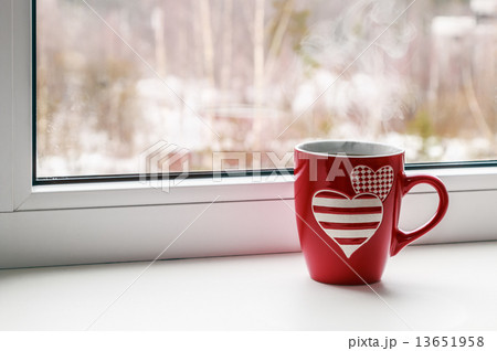 cup with hearts stands on a window 13651958