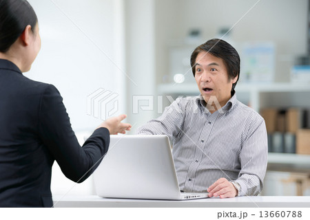 室内でセールスレディーの説明を受けている、カジュアルウェアー姿の中年男性 13660788